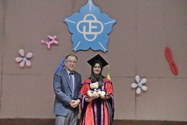 身穿學位服外國畢業生與陳建易教授於大禮堂合影