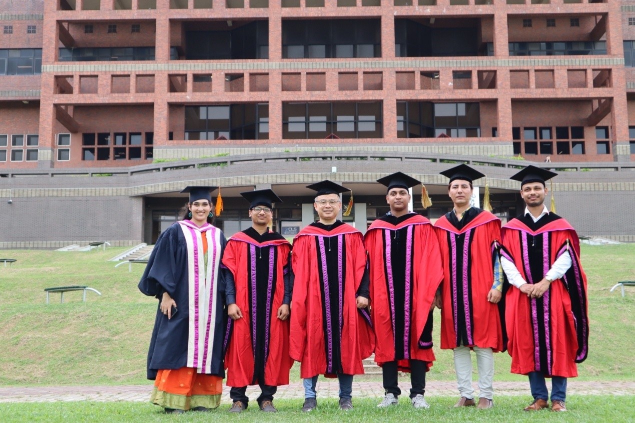 身穿學位服外國學生與陳建易教授於中正大學圖書館前的鳳凰大道合影
